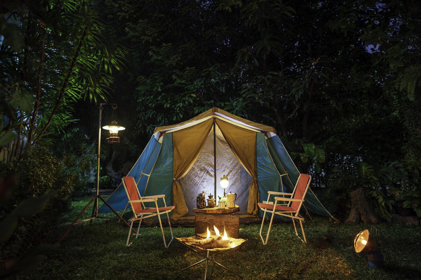 Clásico cabina carpa, antiguo petróleo lámpara, retro sillas, grupo de cámping carpas con al aire libre hacer cafe instalaciones en de madera mesas en un bosque cámping zona en el bosque. foto