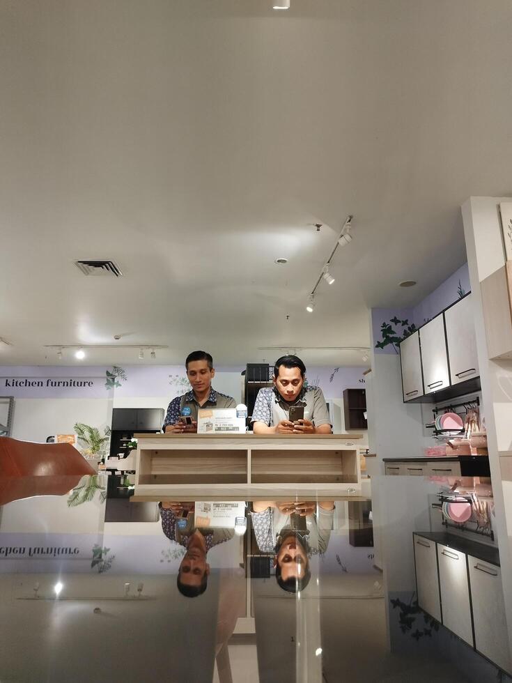 Surabaya, Indonesia, Aug 10, 2022 - Reflection of 2 adult men relaxing on a table photo