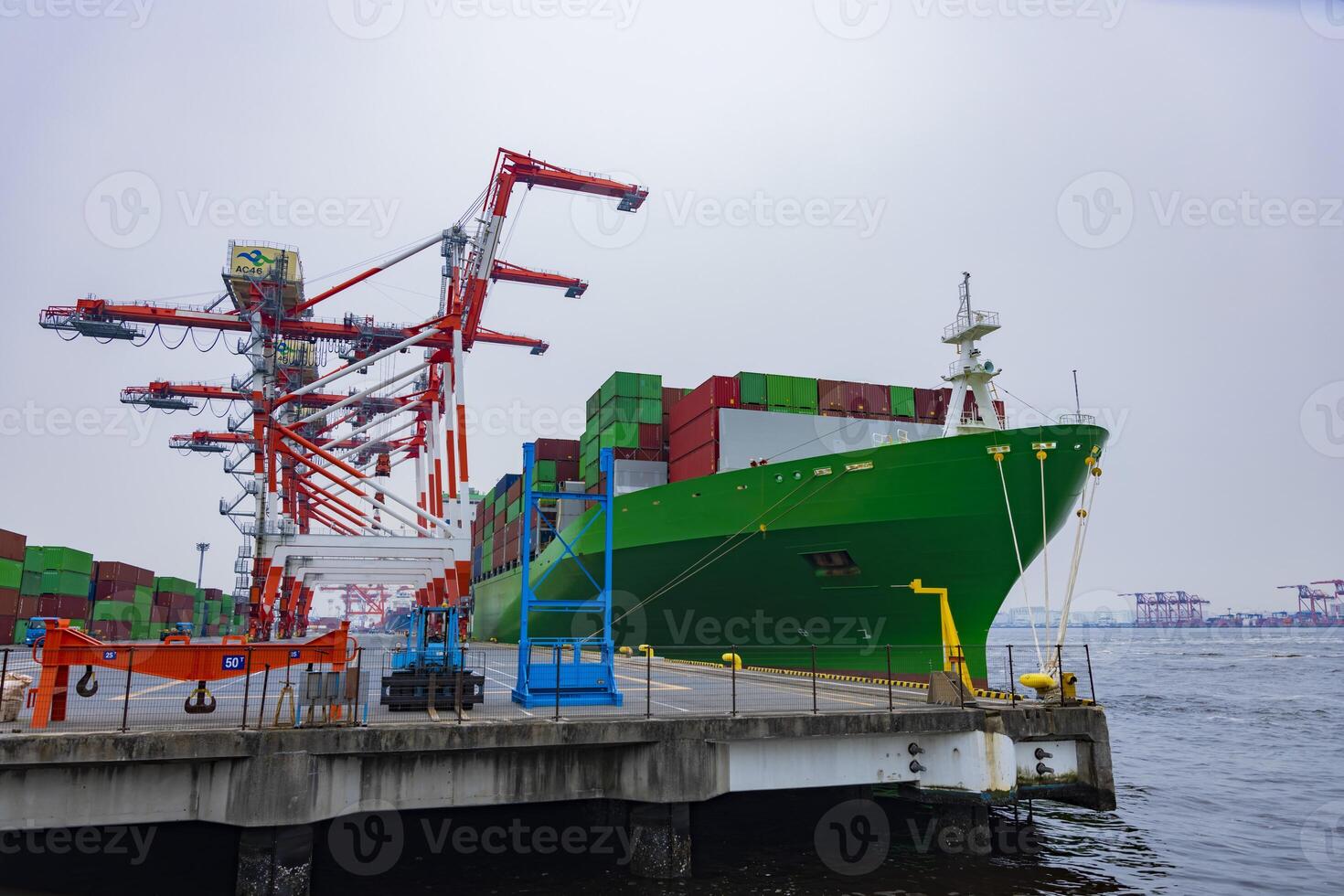 Industrial cranes and a large ship near the container wharf cloudy day wide shot photo