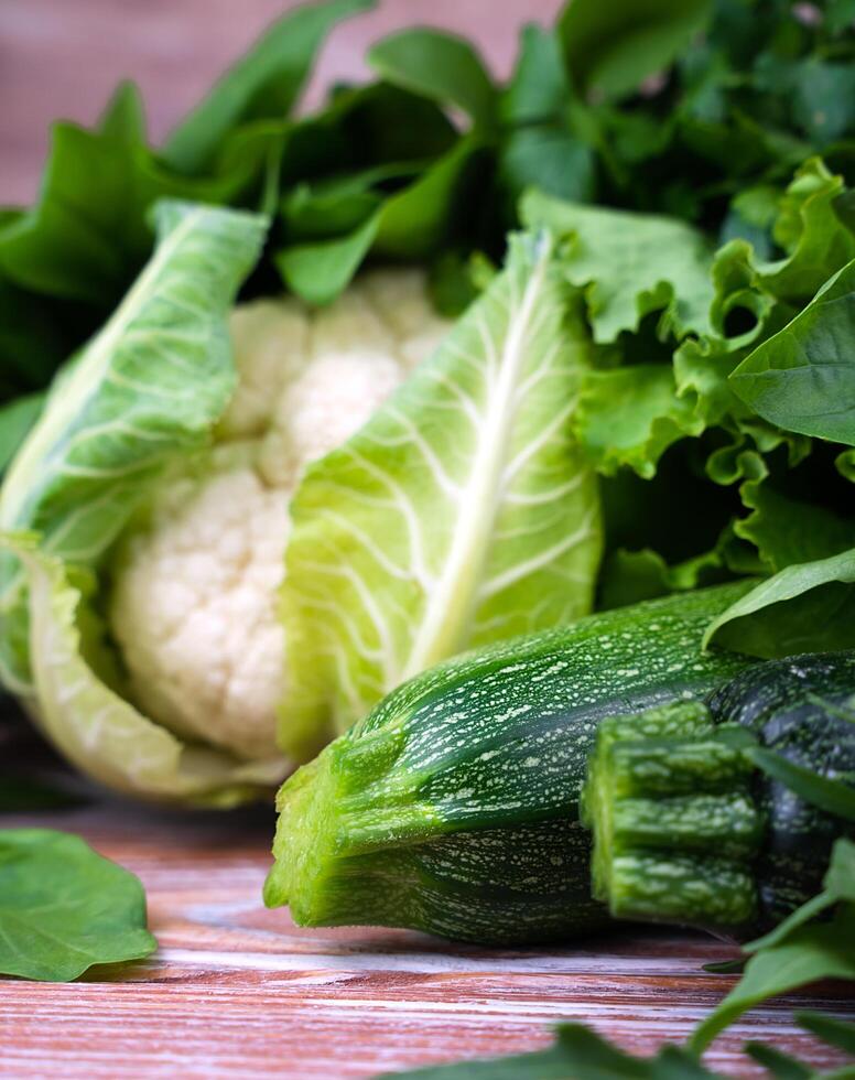 calabacín, coliflor y un variedad de verde frondoso vegetales en un de madera antecedentes. de cerca. selectivo enfocar. foto