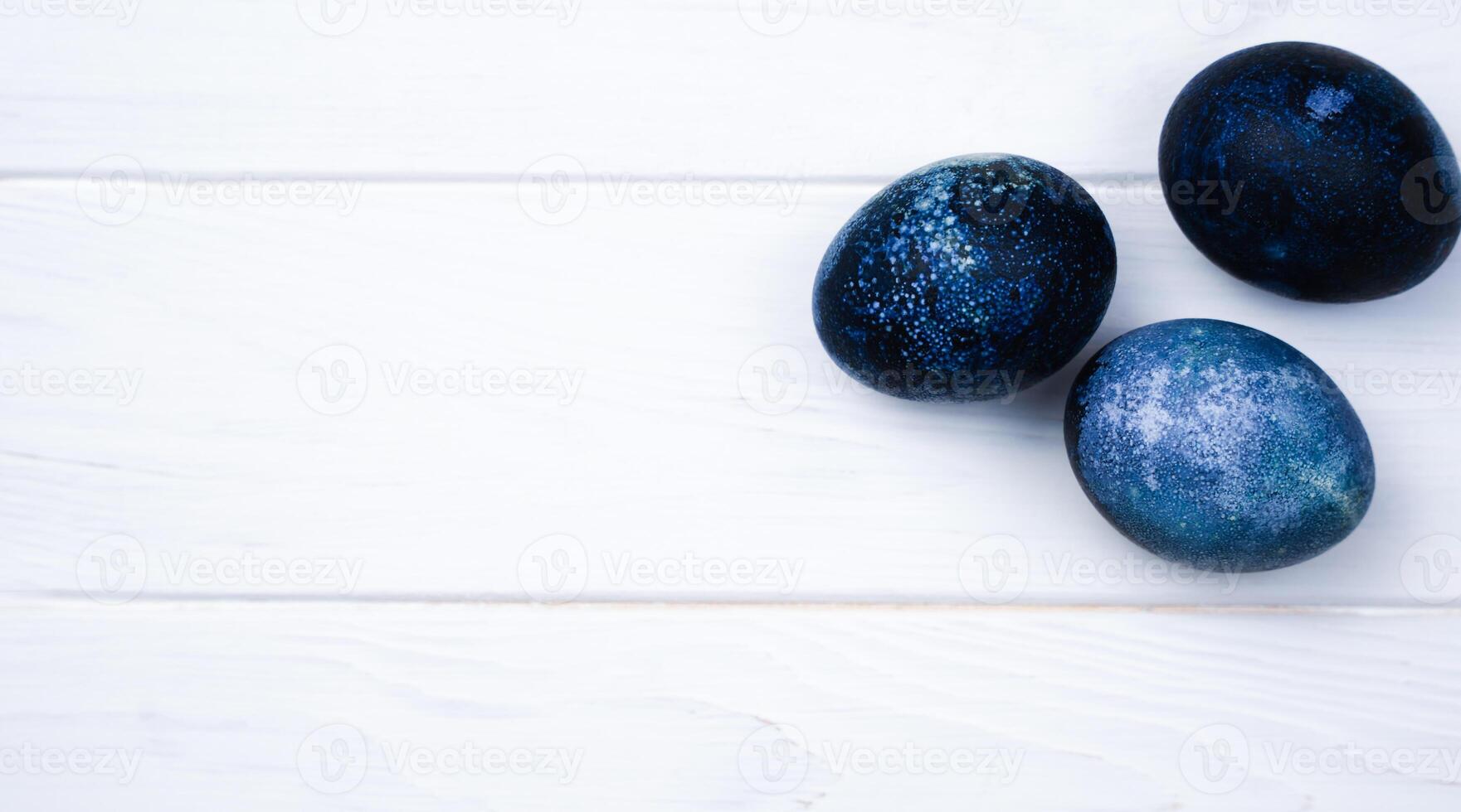 Easter eggs painted with natural dye in blue on the white wooden background. Banner. Close-up. Top view. Place for text. photo