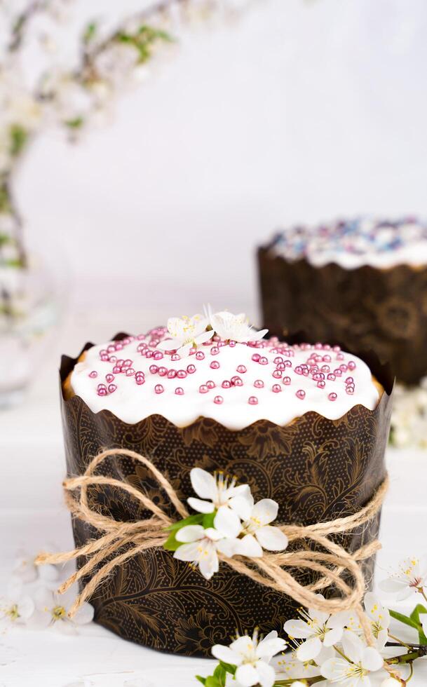 Easter cake decorated with white icing and a sprig of cherry blossoms. Christian traditions. Close-up. Selective focus. photo