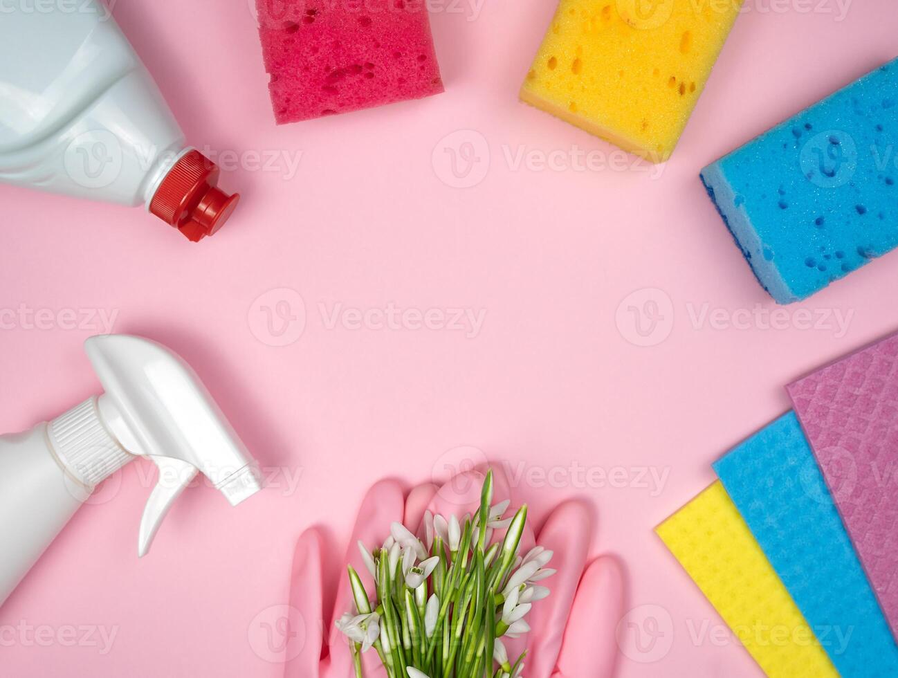 Detergent and cleaning products, kitchen sponges, rubber gloves lie in the shape of a frame on a pink background. Spring cleaning. Top view. Flatlay. Copy space. photo