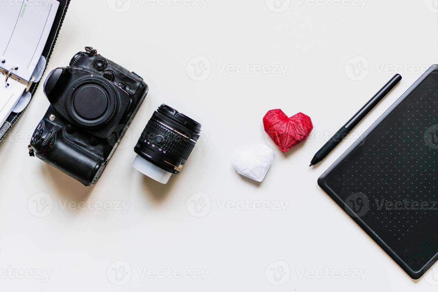 Graphic designer workstation with dslr, lens, agenda, stylus and heart printed in 3d photo