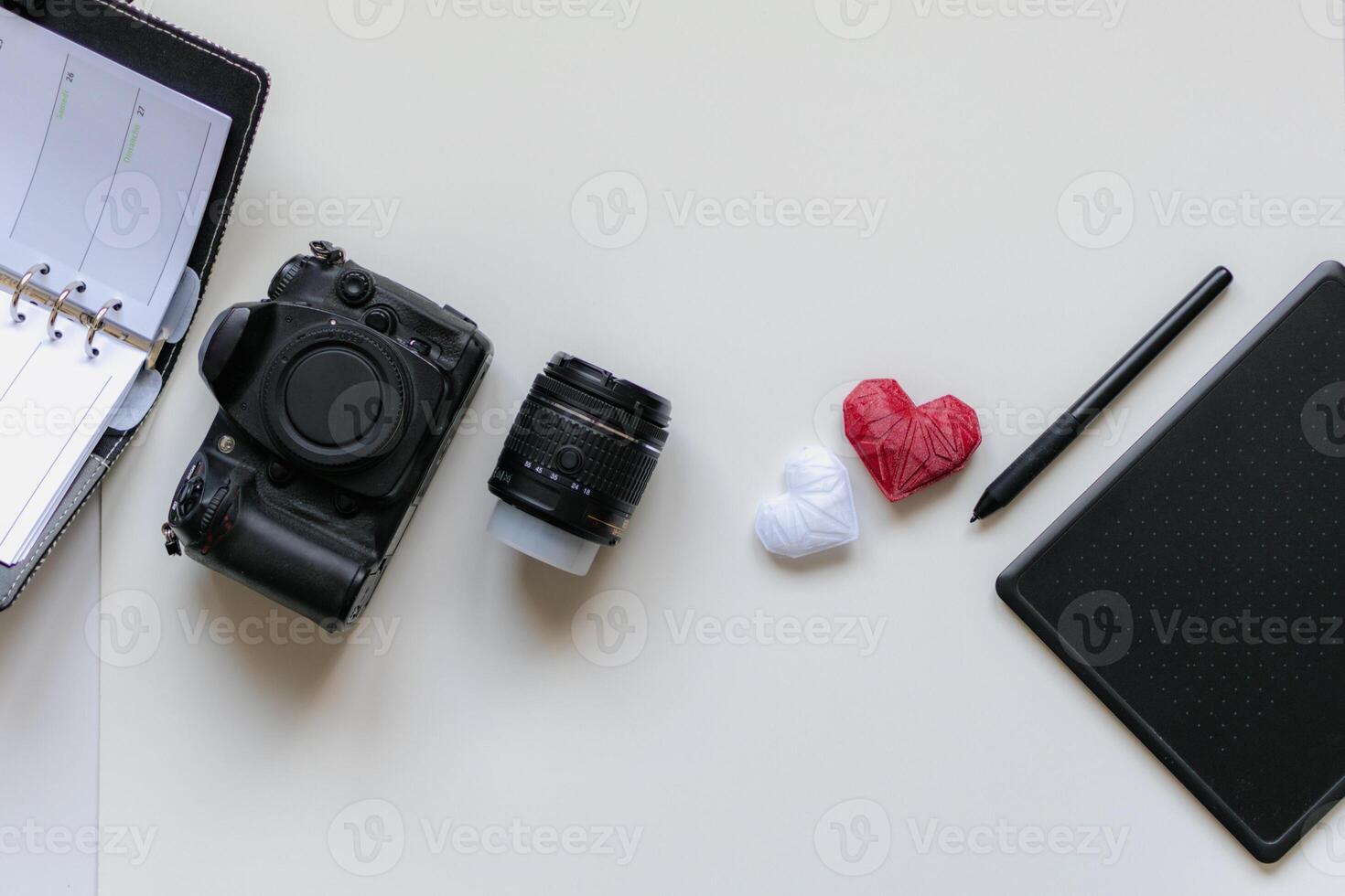 Graphic designer workstation with dslr, lens, agenda, stylus and heart printed in 3d photo