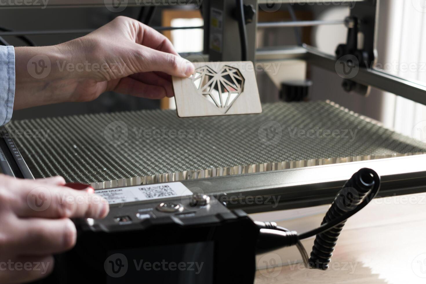 Laser engraving and cutting, woman holding an example of a cut out wooden heart photo