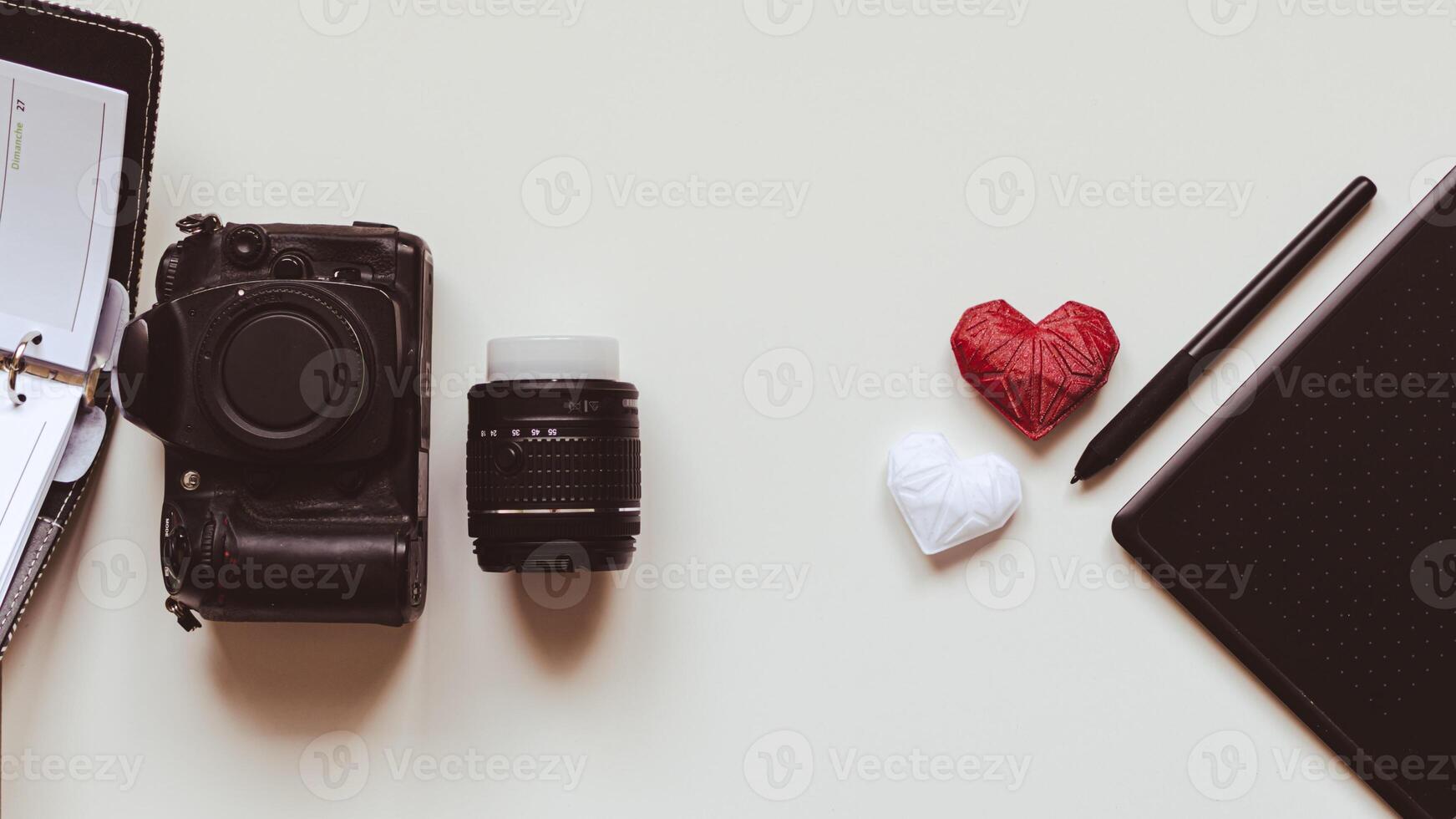 gráfico diseñador puesto de trabajo con cámara réflex digital, lente, agenda, aguja y corazón impreso en 3d foto