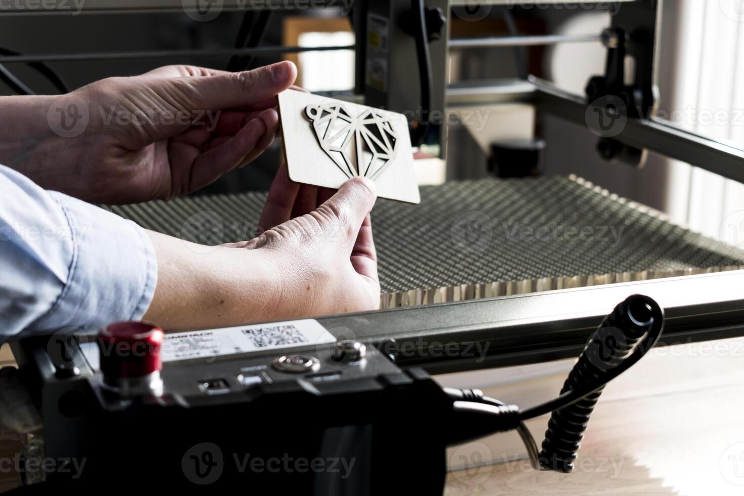 Laser engraving and cutting, woman holding an example of a cut out wooden heart photo