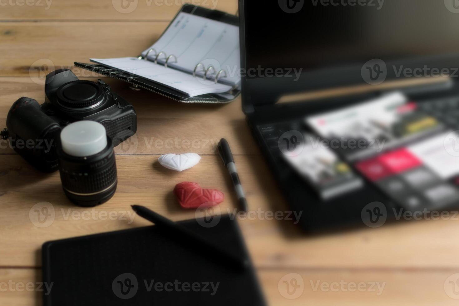 Graphic designer workstation with dslr, lens, laptop, agenda, stylus and 3d objects photo