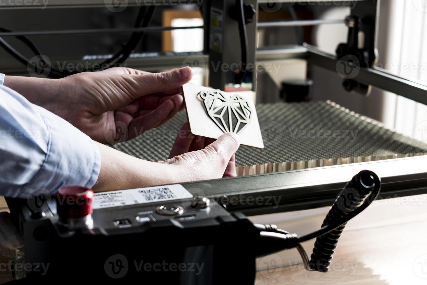 Laser engraving and cutting, woman holding an example of a cut out wooden heart photo