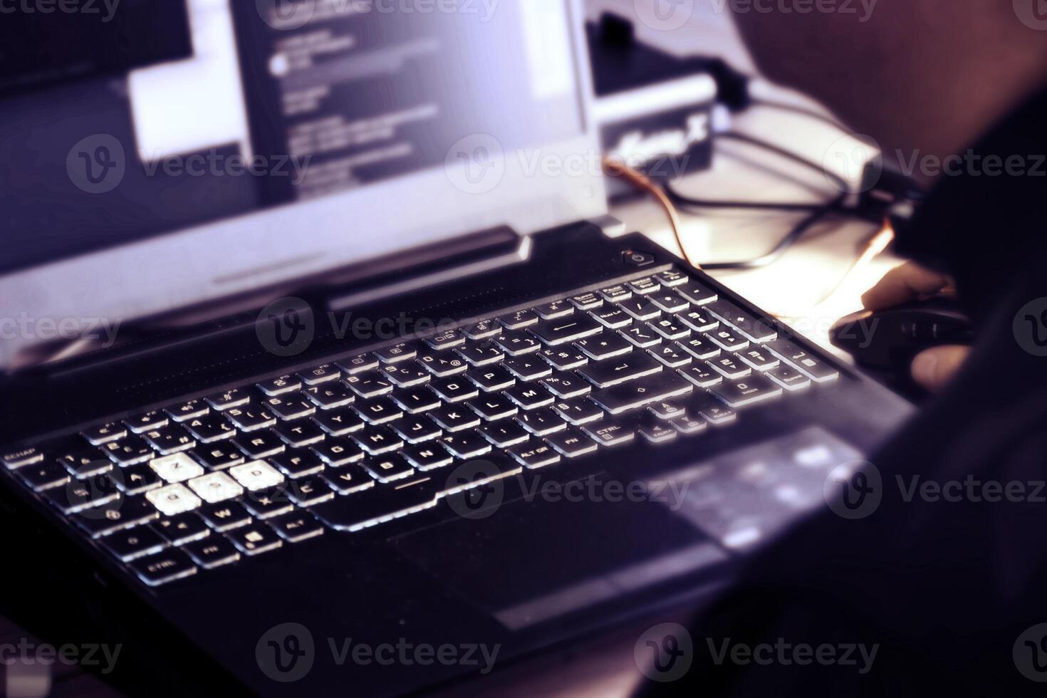 Close up of man's hand using wireless mouse and laptop computer with blue backlit keyboard photo