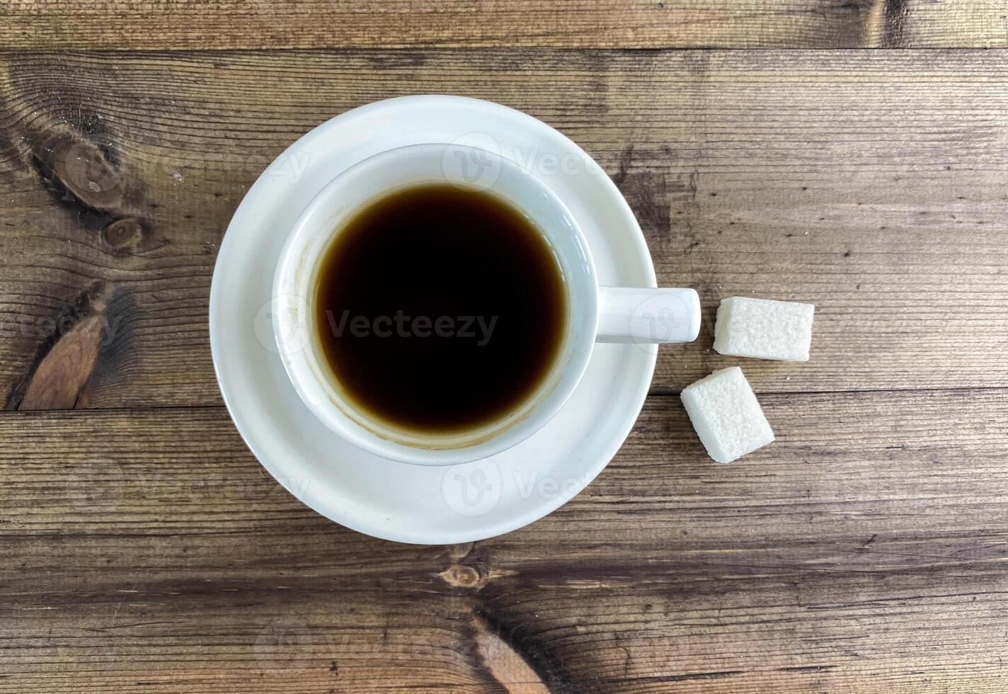 Coffee in a cup and sugar on the table, top view. photo