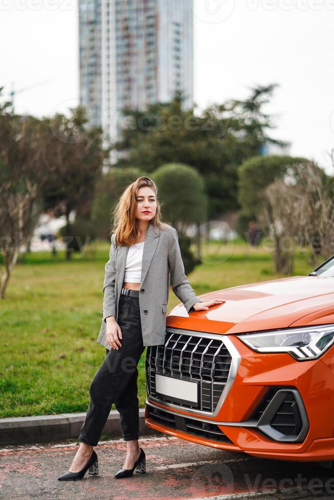 mujer en pie siguiente a naranja coche foto