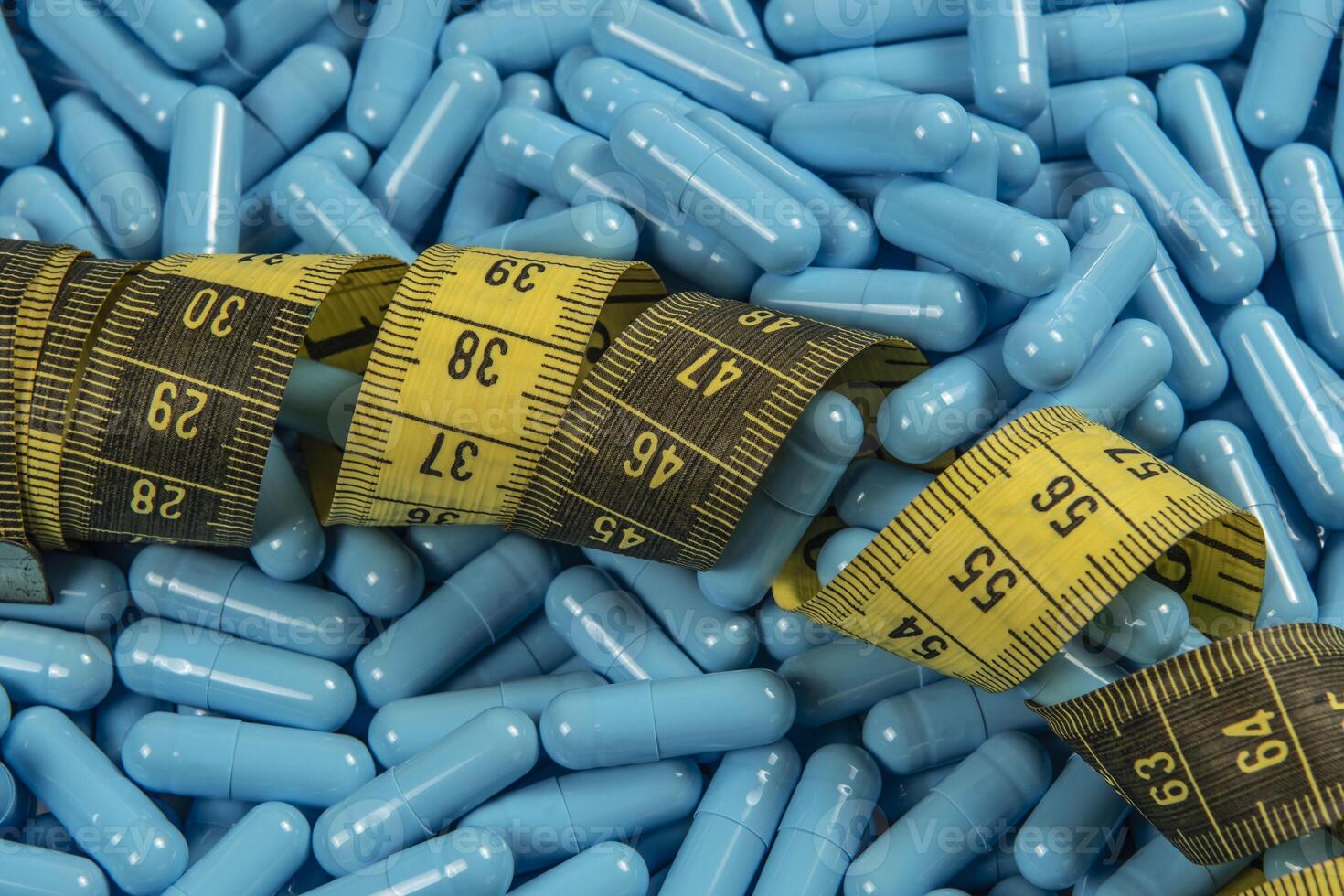Blue weight loss pills and measuring tape symbolizing slimming photo
