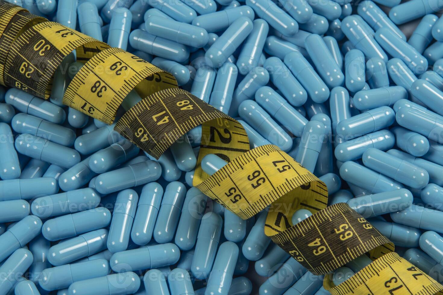 Blue weight loss pills and measuring tape symbolizing slimming photo