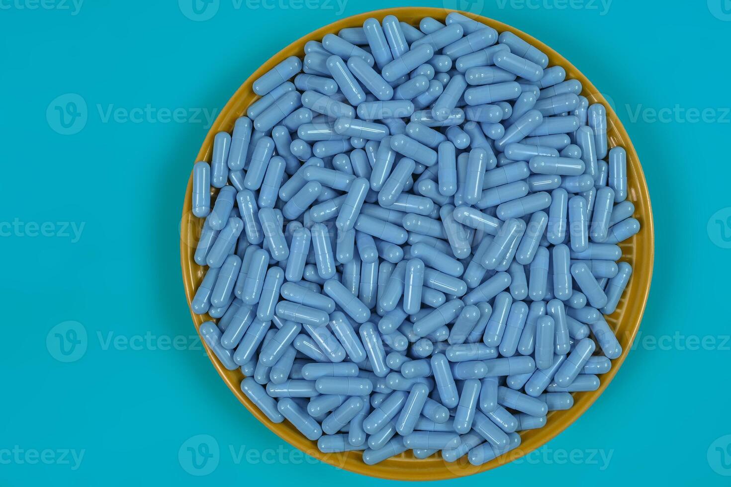 Yellow plate full of blue medicine capsules representing drug overdose photo