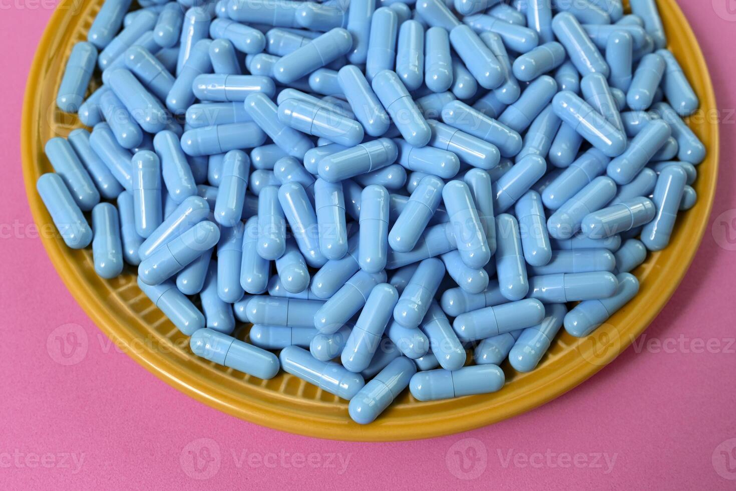 Yellow plate full of blue medicine capsules representing drug overdose photo