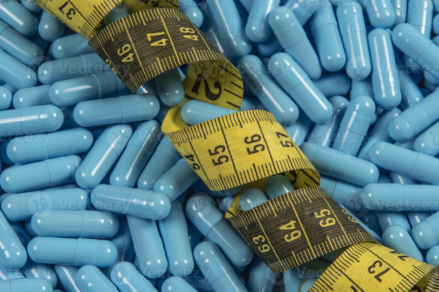Blue weight loss pills and measuring tape symbolizing slimming photo