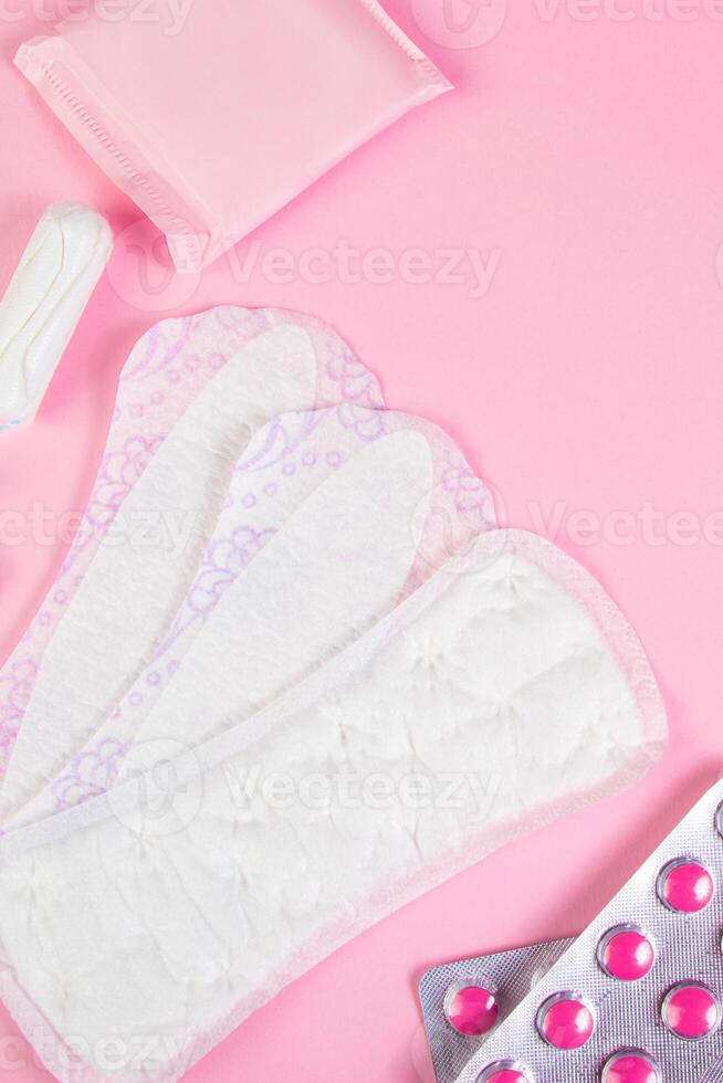 Set of feminine hygiene products for menstruation. Sanitary pads, tampons, pills on pink background. photo