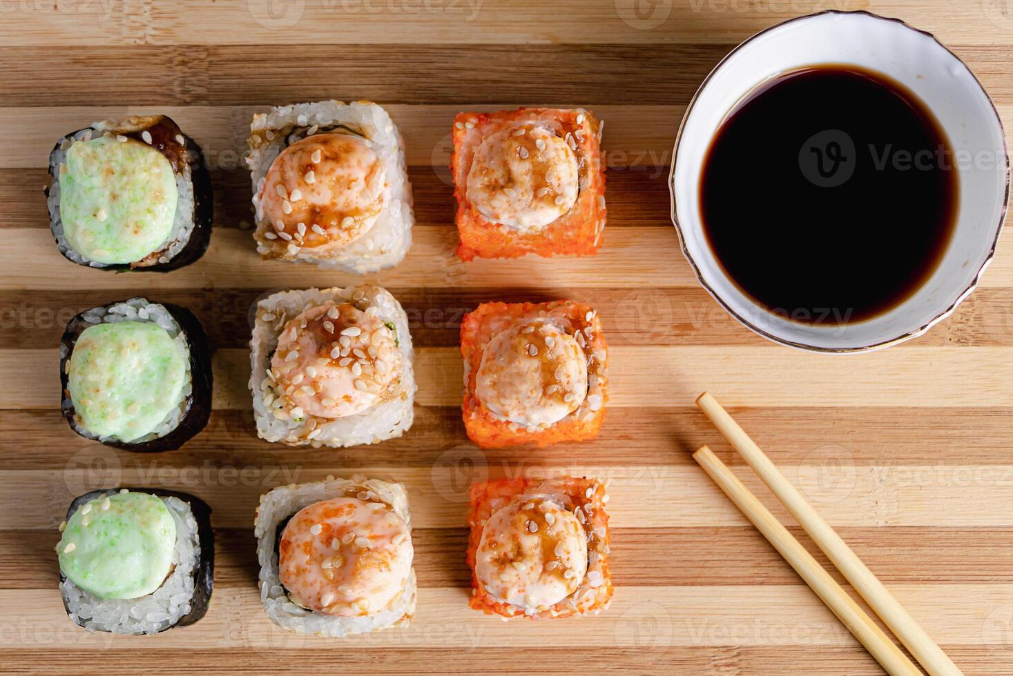Set of sushi rolls on bamboo serving tray. Uramaki roll, chopsticks and soy sauce. photo
