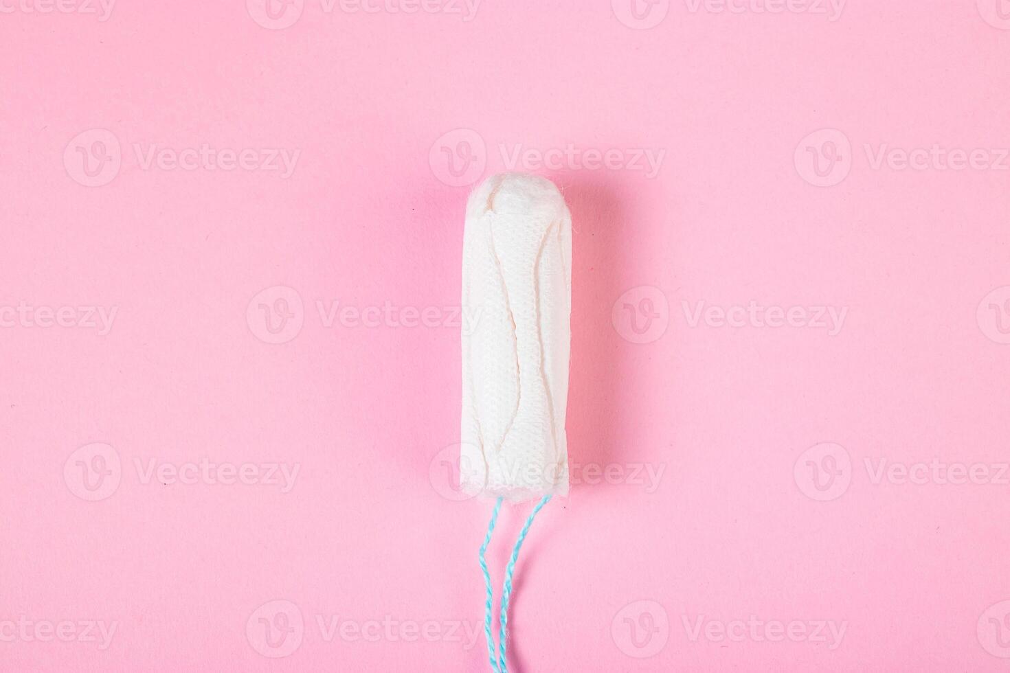 Hygienic cotton tampon on pink background. Feminine menstrual hygiene product. photo