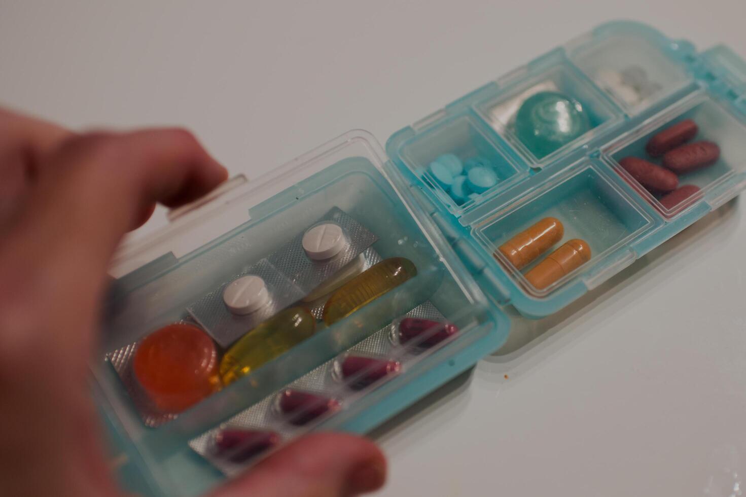 Colorful pills in a dispenser, human hand photo