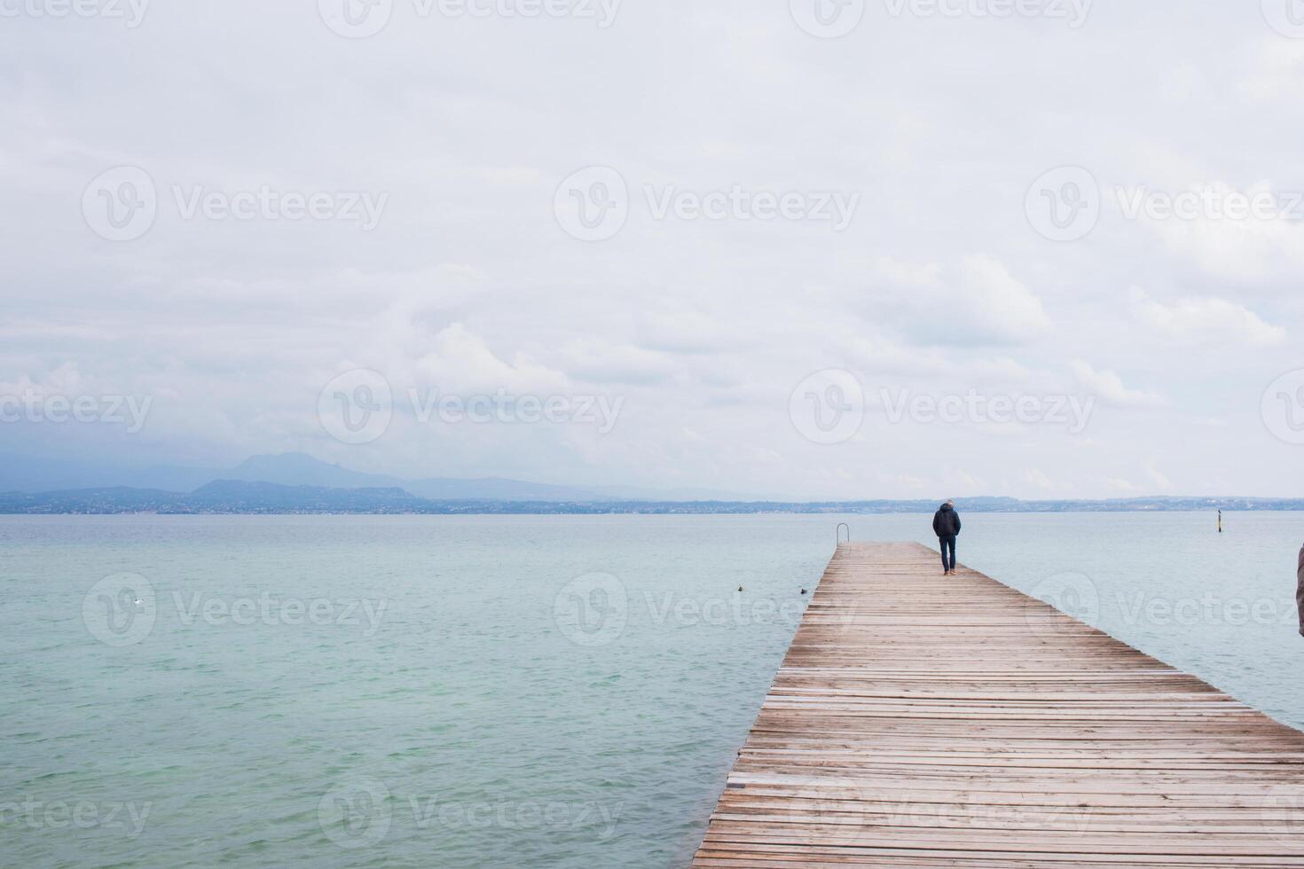 Unrecognizable man standing on pier over Garda lake photo