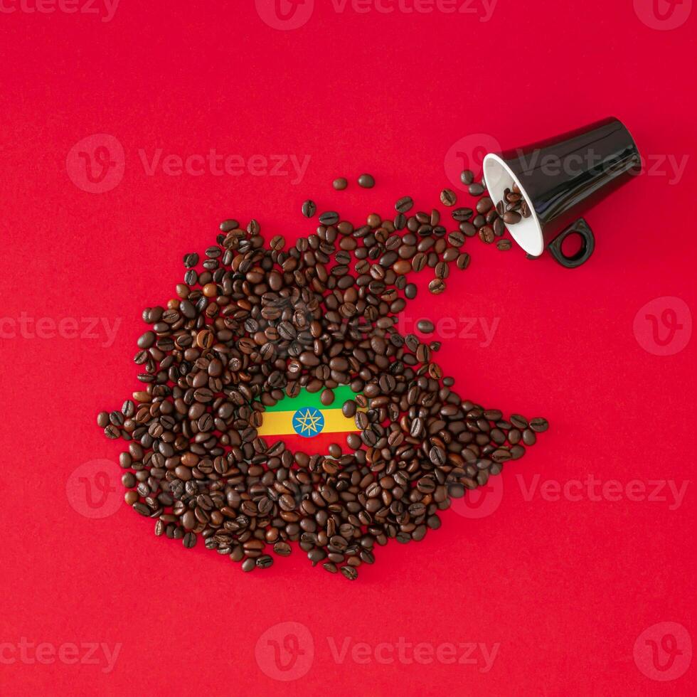 Creative composition made with coffee cup, map of Ethiopia made with roasted coffee beans and Ethiopian flag on red background. Minimal layout. Ethiopia, the home of coffee concept. Flat lay. photo