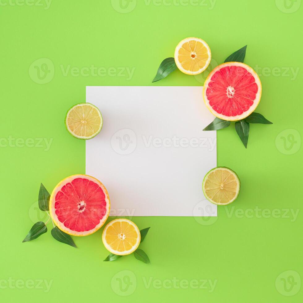 Trendy layout made with grapefruit, lime, lemons, green leaves and paper card note copy space on light green background. Creative food concept. Minimal citrus fruits summer idea. Flat lay. photo