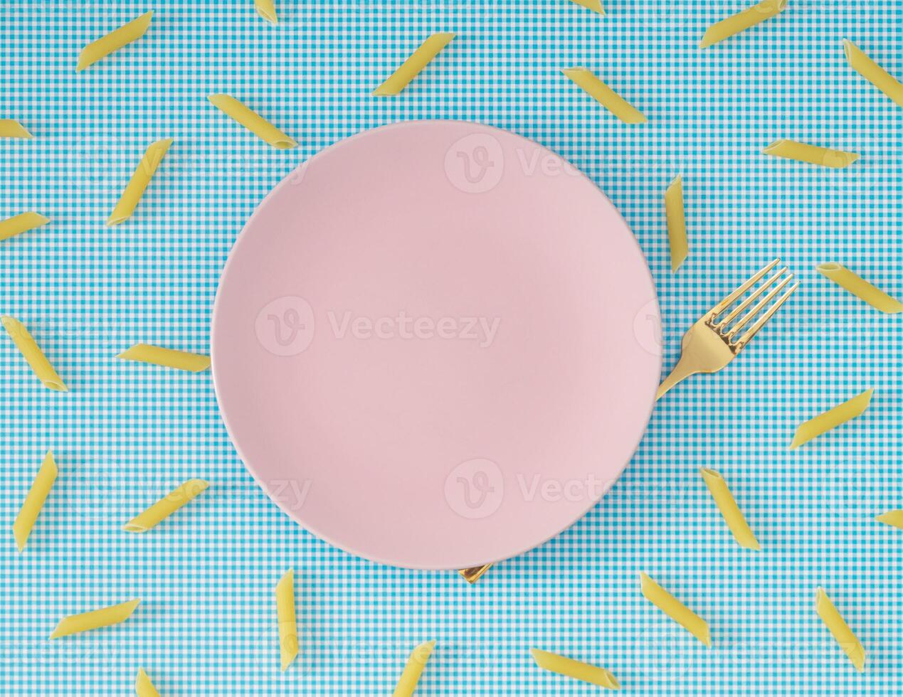 Trendy food pattern made of pasta penne rigate, pink plate and golden fork on white and blue background. Minimal food concept. Creative pasta pattern background. Flat lay, top of view. photo