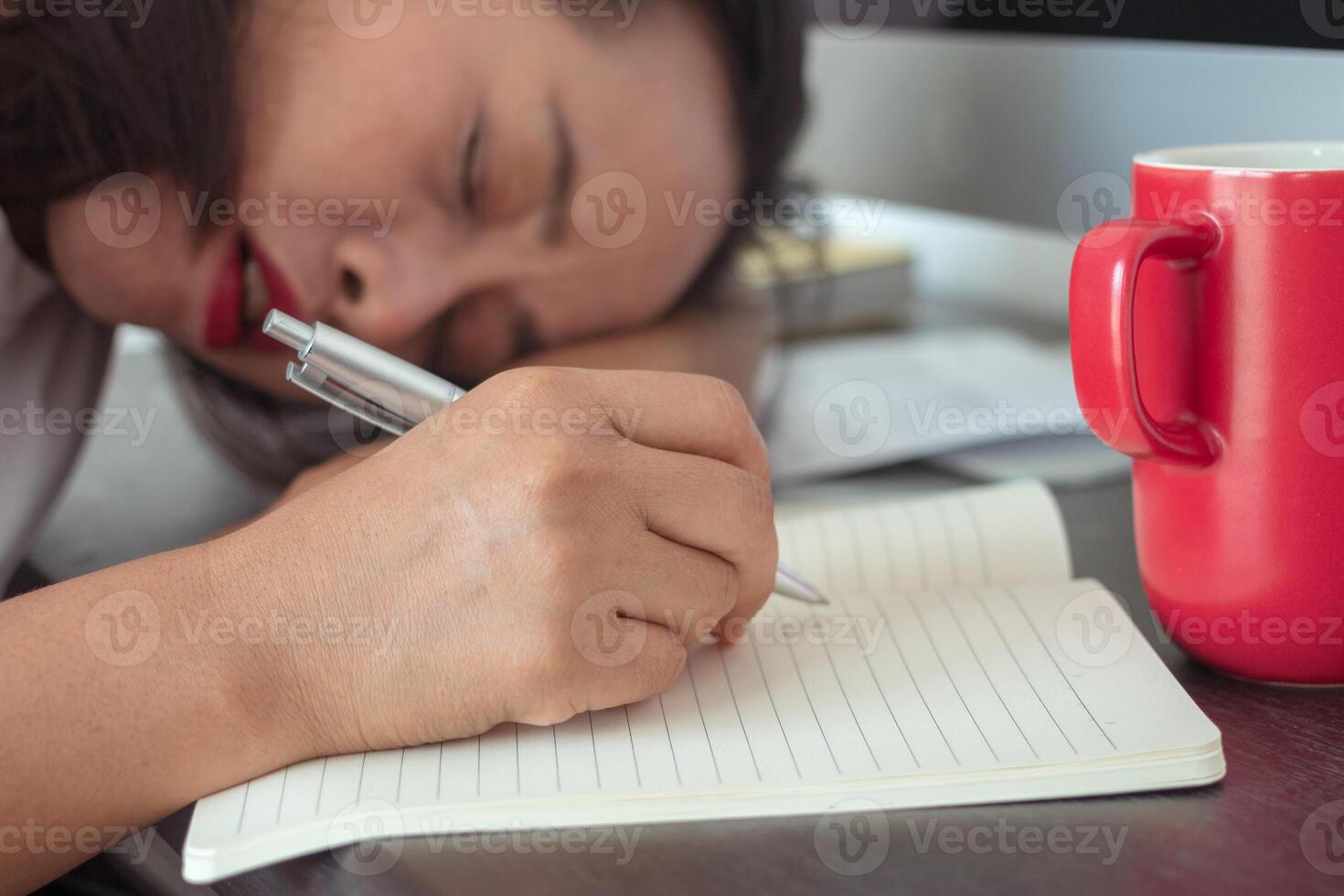 very sleepy and tired business woman on desktop computer, red coffee mug. photo