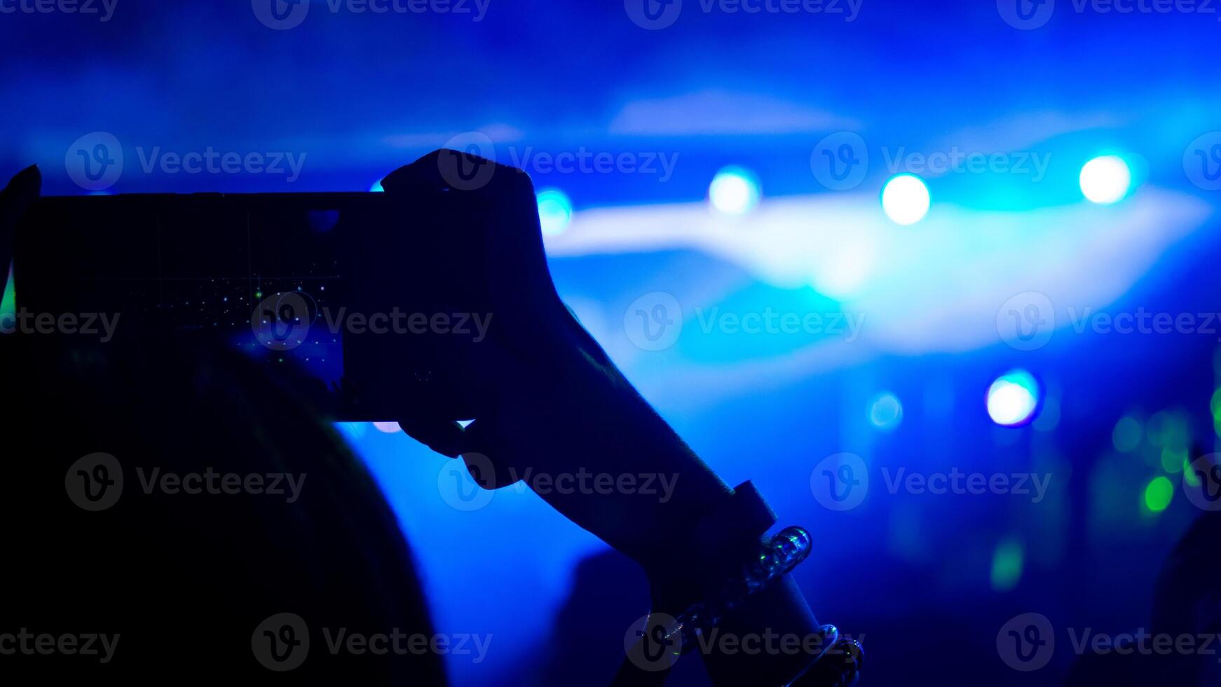 Woman taking a photo with phone at music event