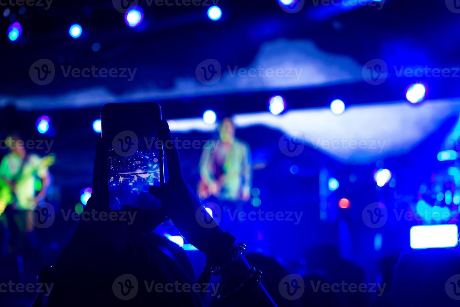 mujer tomando un foto con teléfono a música evento