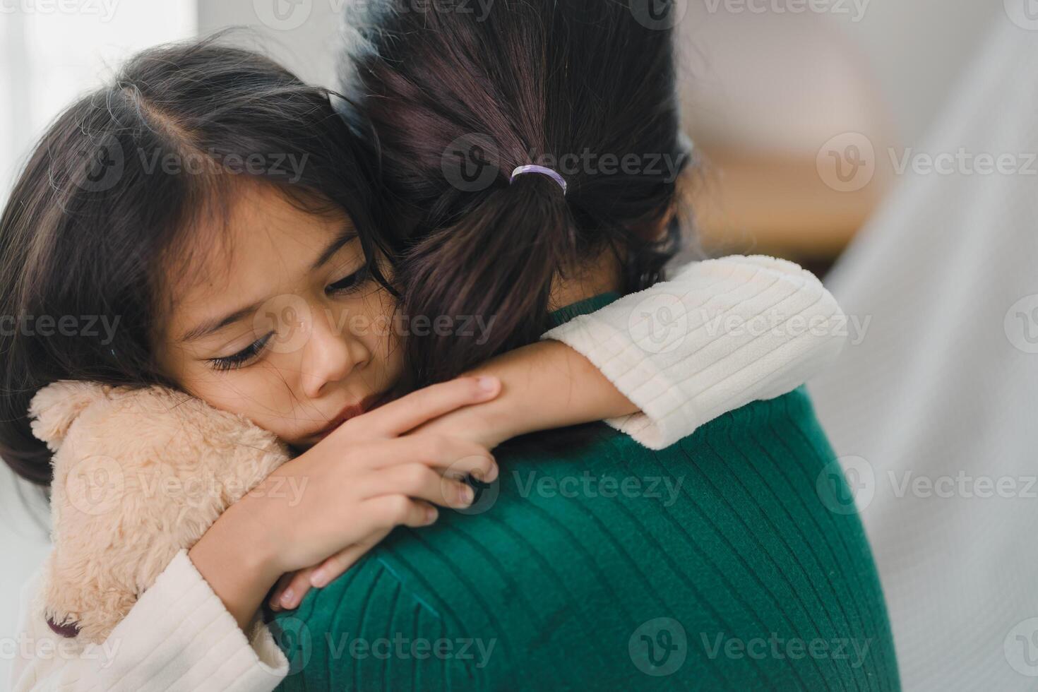 A woman is hugging a child and holding a stuffed animal photo