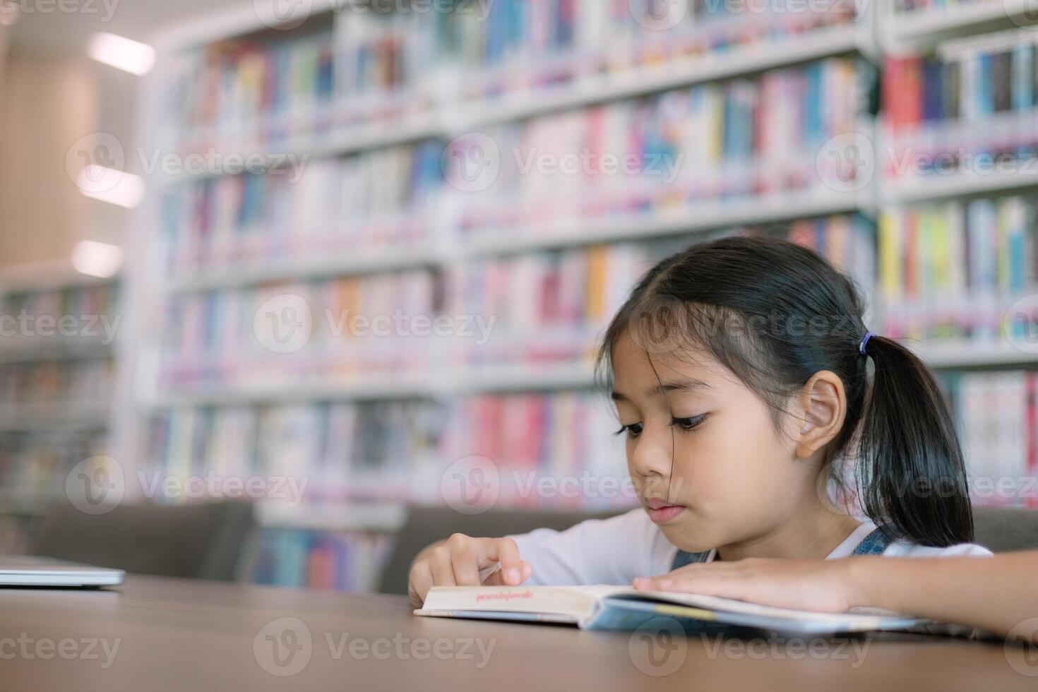 un joven niña es leyendo un libro en un biblioteca foto