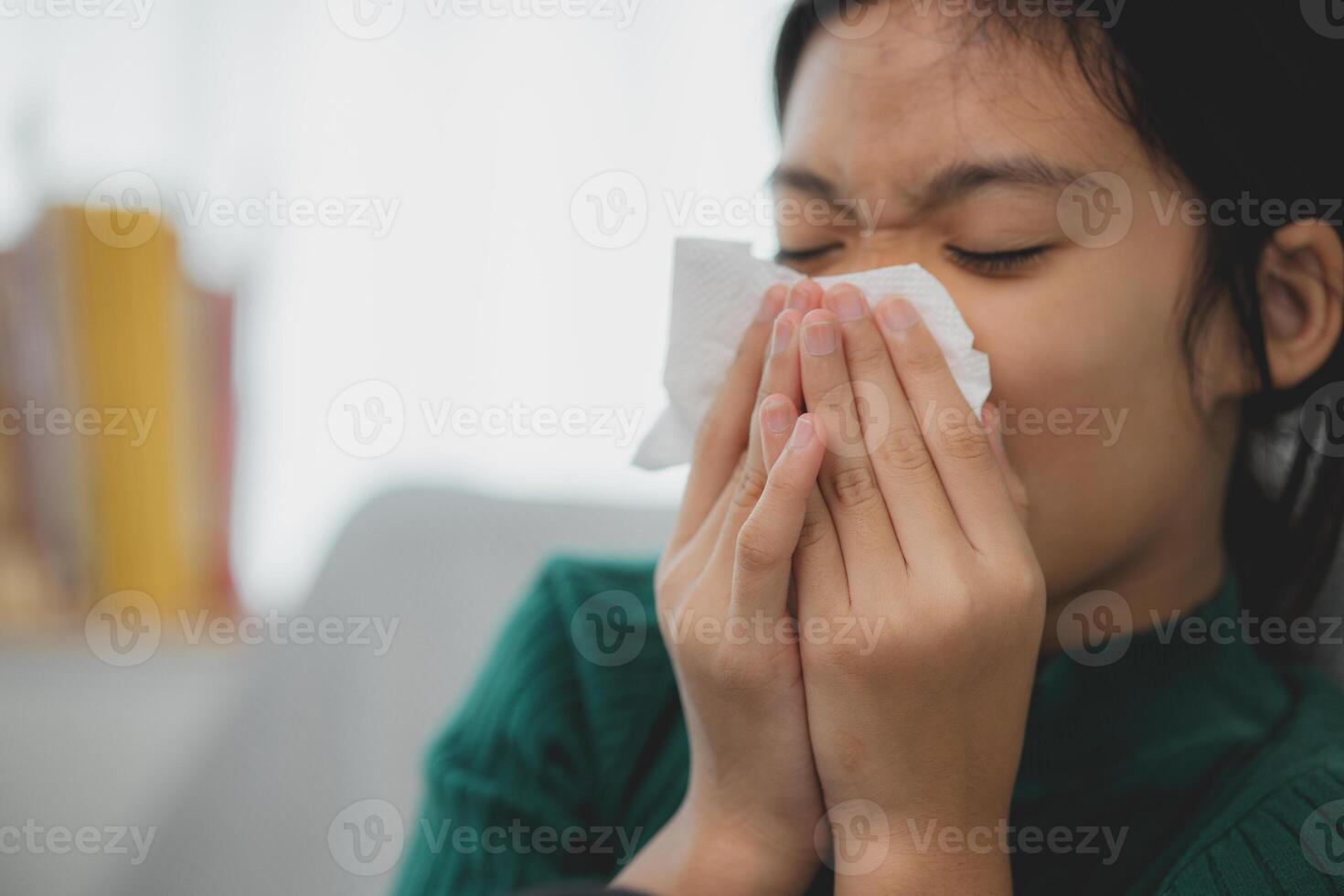 un insalubre niño soplo su nariz dentro un tejido, un niño sufrimiento desde corriendo nariz o estornudos, un niña atrapando un frío cuando el temporada cambiar, un infancia limpiando nariz con un pañuelo de papel foto