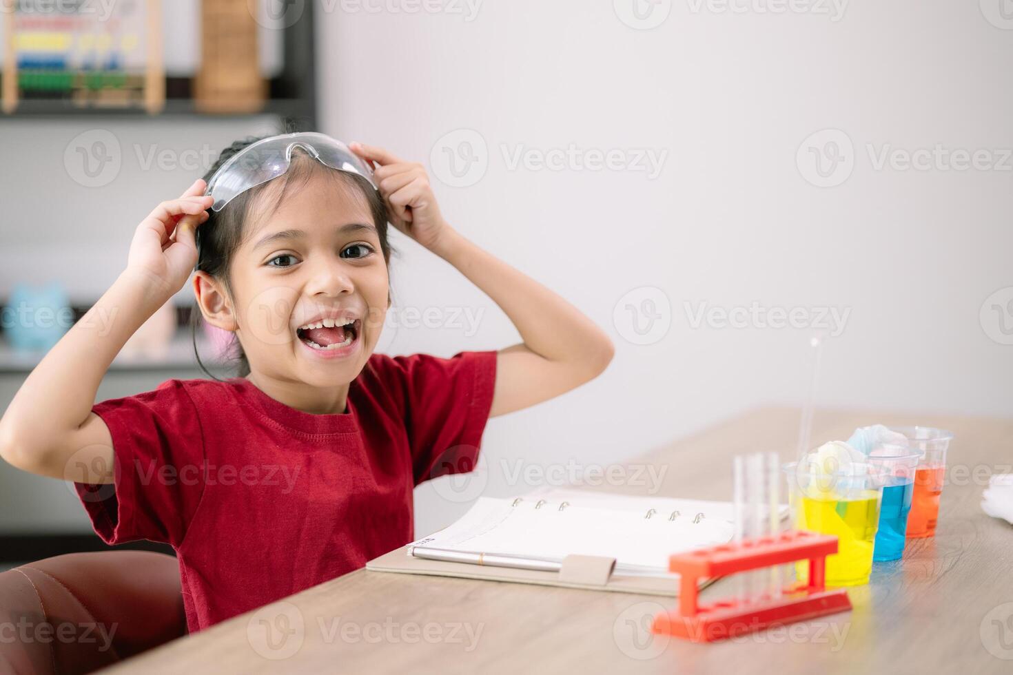 Asian girl making Walking Water experiment. Food color is added to the water in the glass, water moves along the paper, and then color is mixed. Concept of science for kid photo