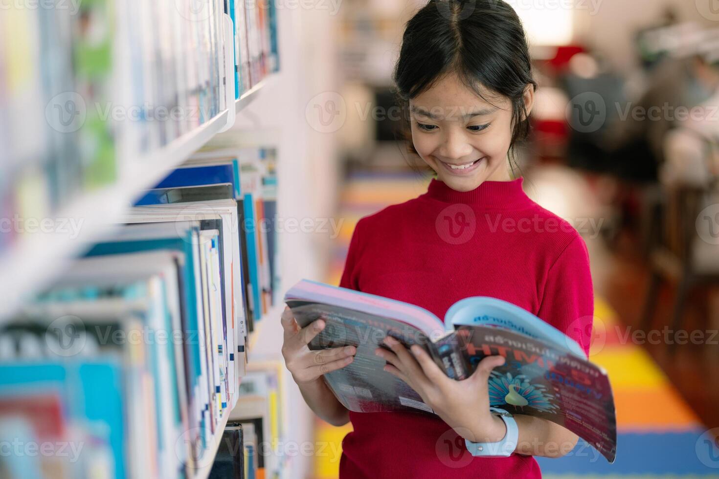 A young girl is reading a book in a library photo