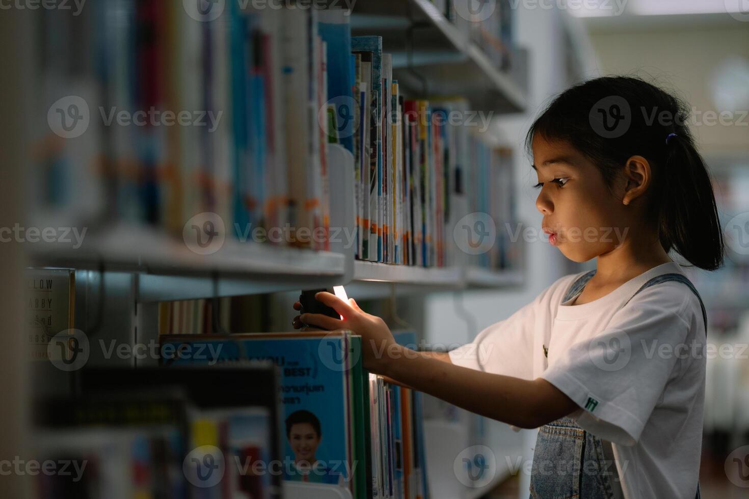 A young girl is looking at a book in a library photo