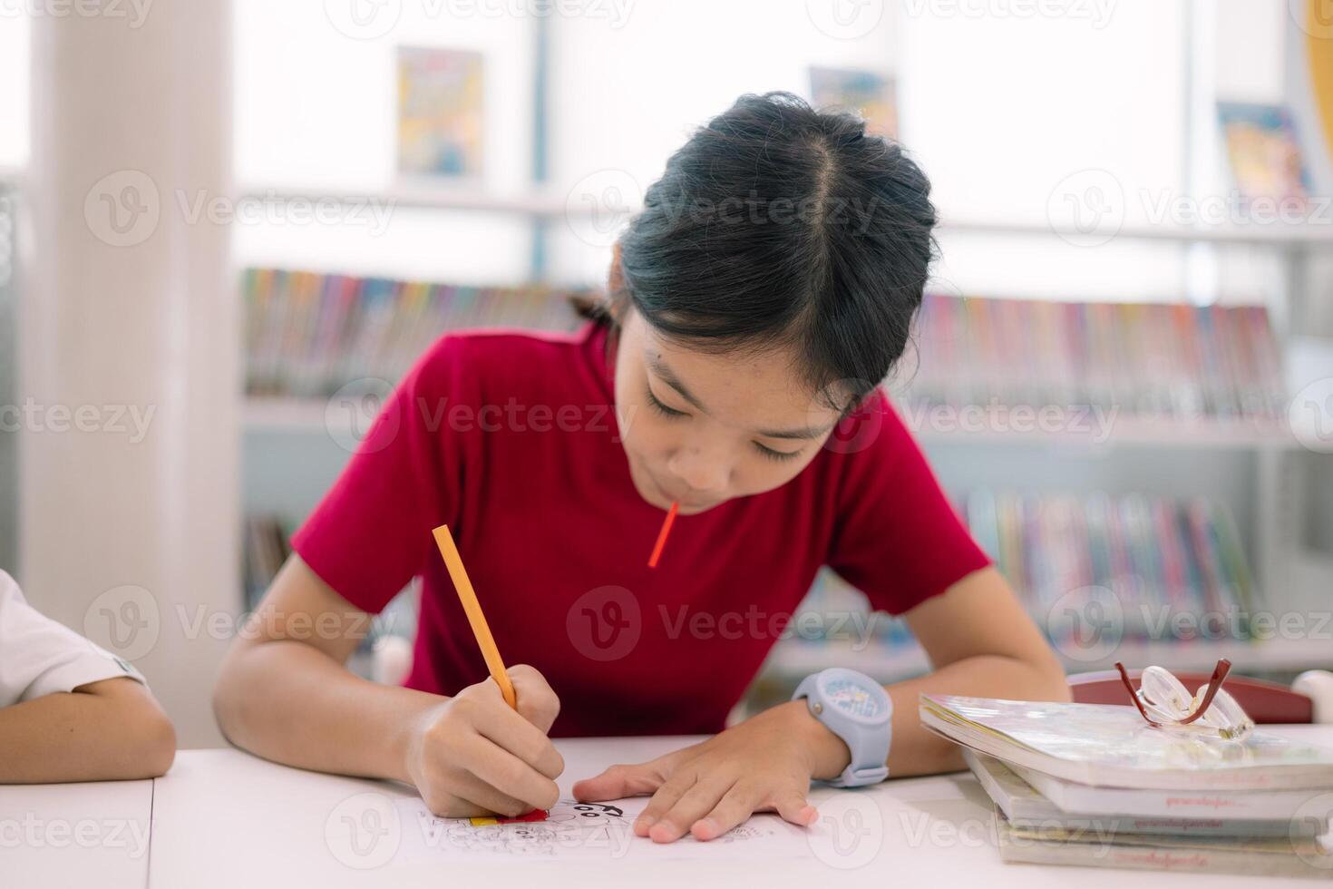 A girl is drawing on a piece of paper with a pencil photo