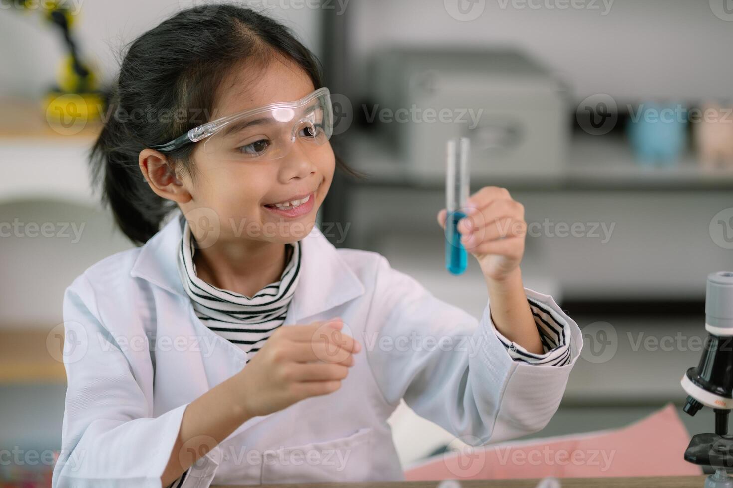 Little cute girl with a microscope holding a laboratory bottle with water experiment study scientists at school. Education science concept. photo