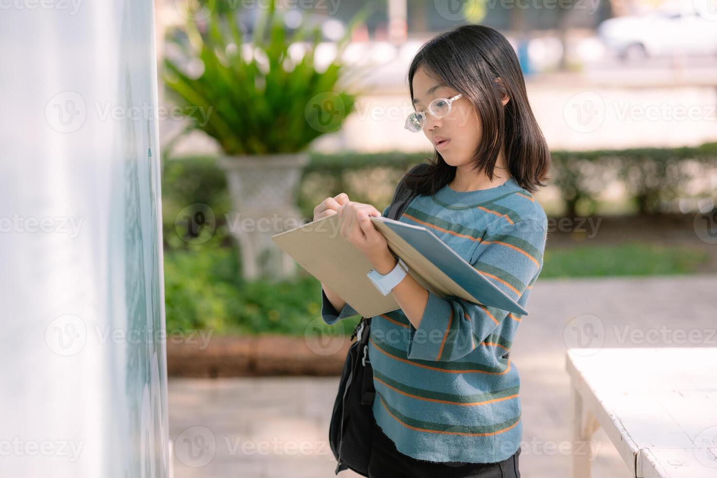 A girl wearing glasses is looking at a white board photo