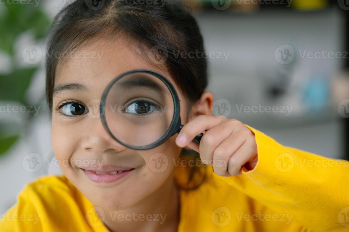A young girl is holding a magnifying glass and looking at something photo