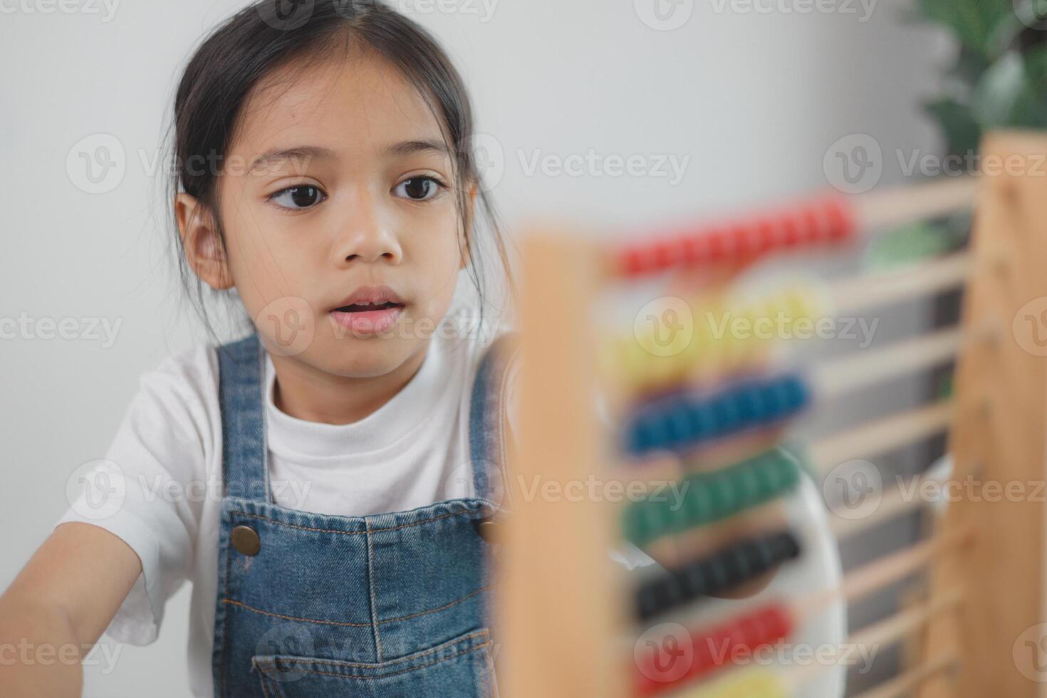 Cute asian child girl learning to count using an abacus in the classroom at kindergarten. photo