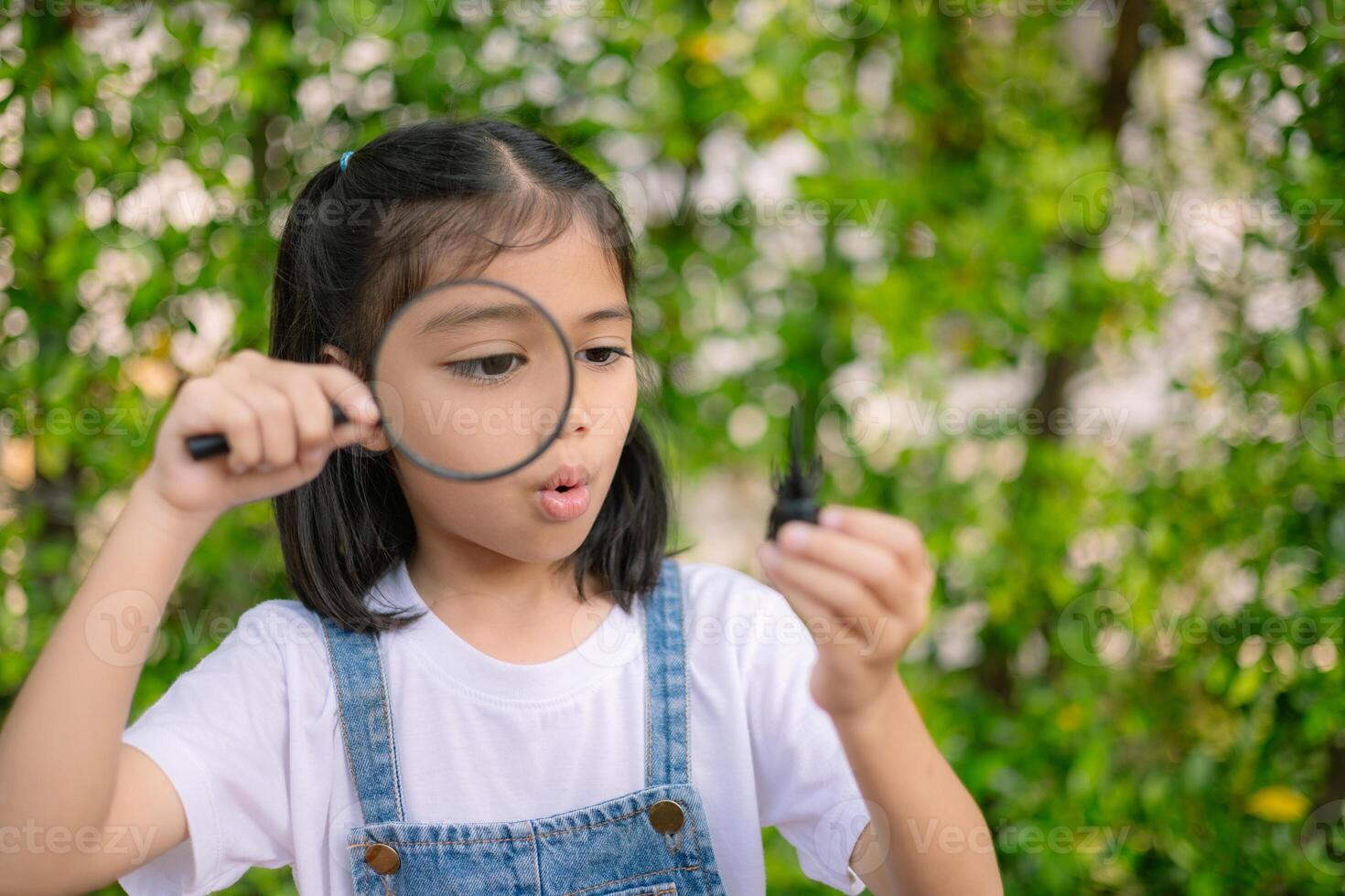 A young girl is holding a magnifying glass and looking at something photo