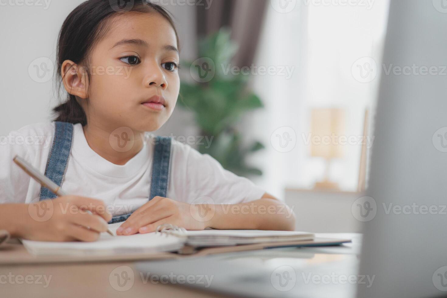 A young girl is sitting at a desk with a laptop open in front of her photo