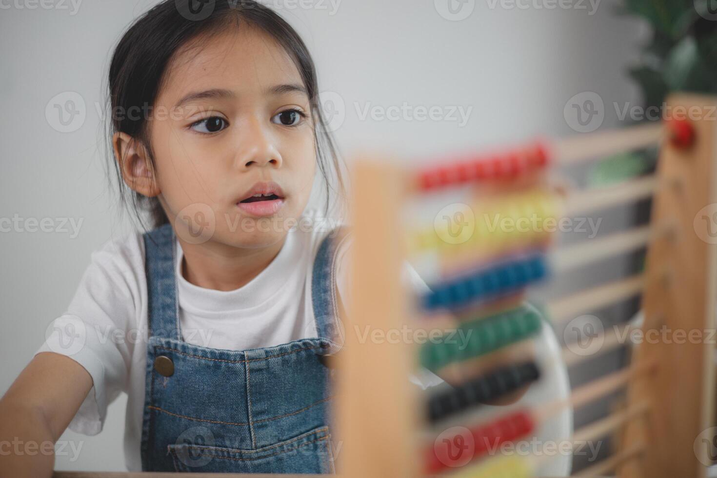 Cute asian child girl learning to count using an abacus in the classroom at kindergarten. photo