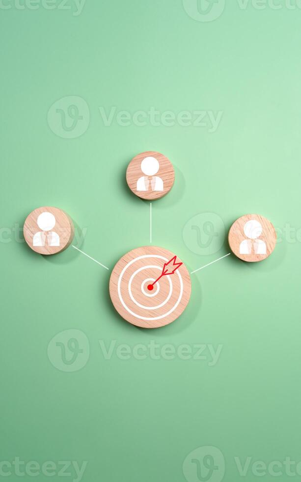 Circular wood with printed target icons and business symbols on green background, business goals and objectives concept, business competition, Customer relationship management concept. photo