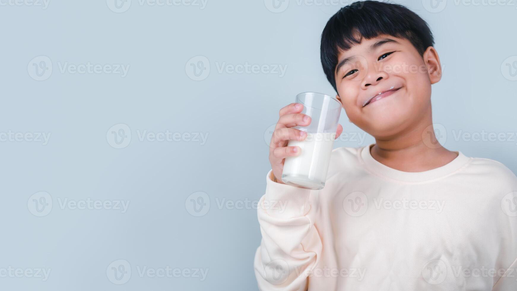 Concept of happy good nutrition, Portrait of a little young handsome kid boy in cream color shirt, Hold drinking milk box mockup, Isolated on white background. photo