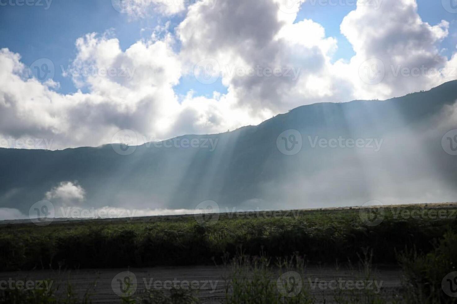 Photo of a valley under a misty mountain